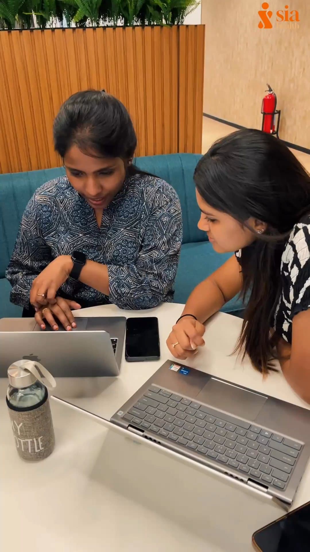 Two Sia Health Coaches working together at a table with laptops